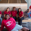 Student staff members in red UHRL staff shirts in front of the Morgan lobby fireplace